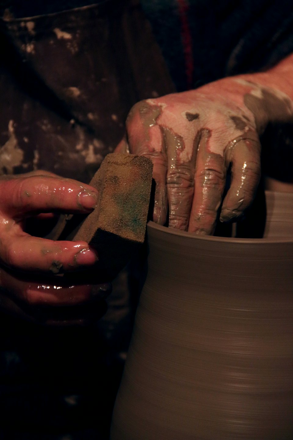 Manos moldeando arcilla húmeda en un torno de alfarero.