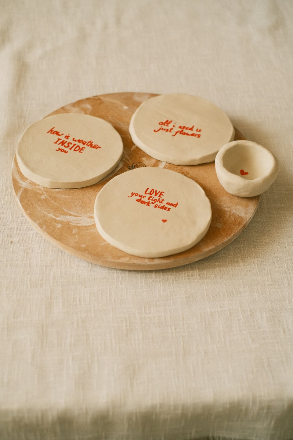 Tabla de madera con posavasos y cuenco de cerámica hechos a mano.