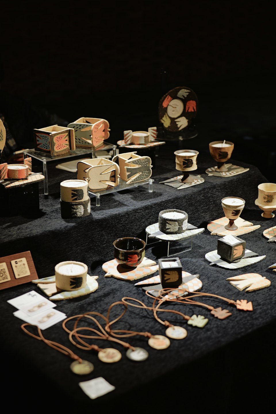Pájaros y recipientes de cerámica hechos a mano sobre una mesa de exhibición oscura.